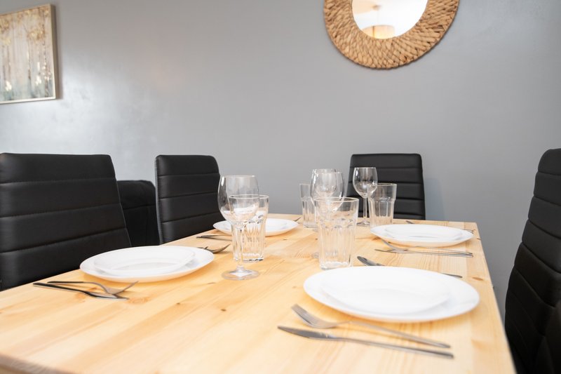 Dining room with wooden table, place settings, black chairs and woven wall decoration