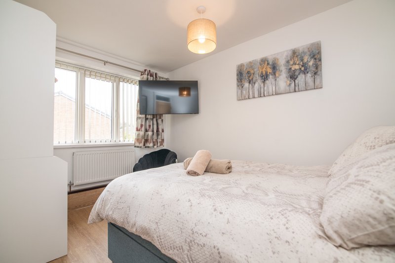 Modern bedroom with double bed, wall-mounted TV, window with blinds and pendant light