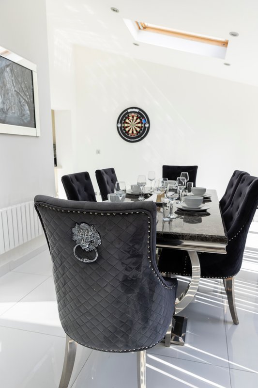 Modern dining room with round table, black upholstered chairs, dartboard wall decor