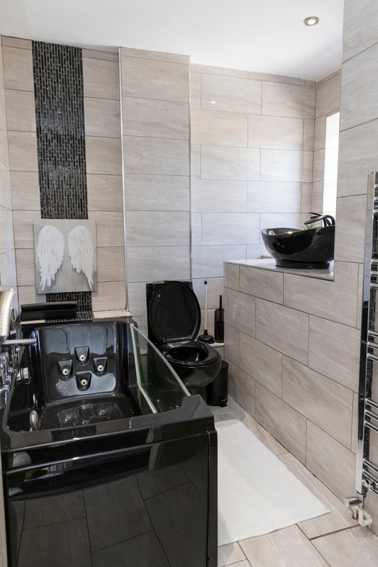 Modern bathroom with beige tile walls, black vanity, and walk-in shower