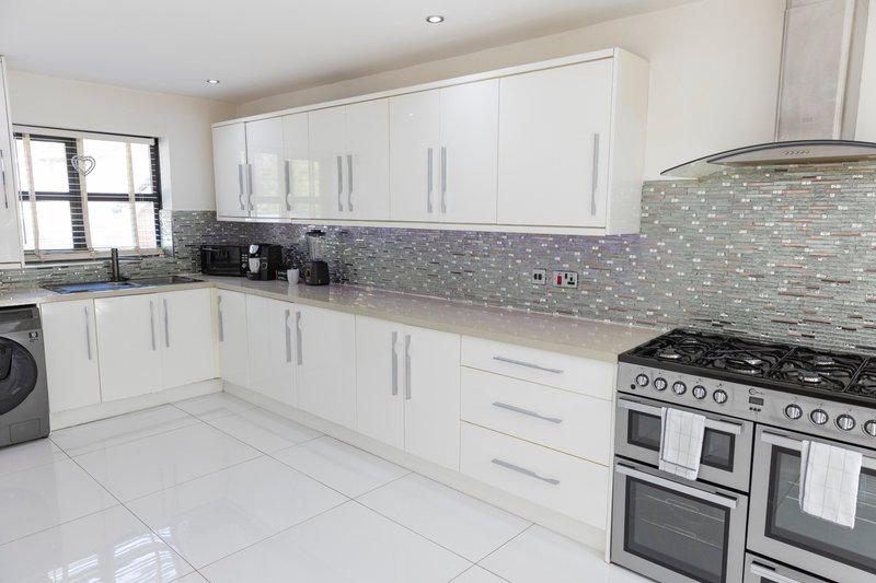 Modern kitchen with white cabinetry, mosaic tile backsplash, stainless steel range and appliances