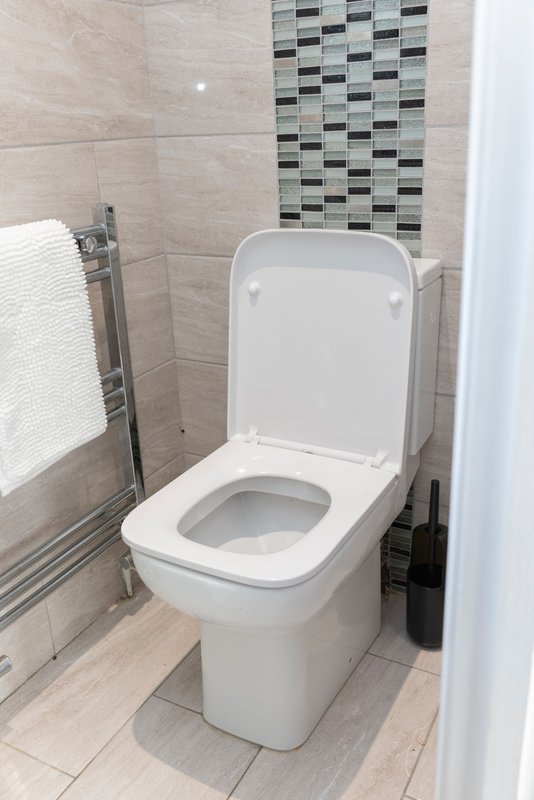 Modern bathroom with white toilet, tiled walls, towel rail and decorative tile feature