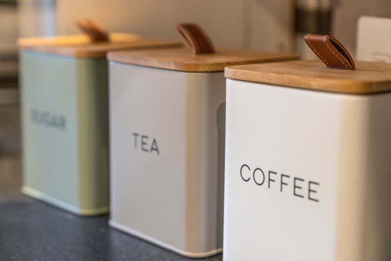 Kitchen counter with three ceramic storage containers labeled for sugar, tea, and coffee