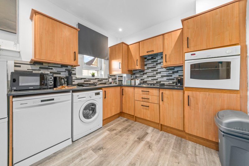 Modern kitchen with wooden cabinetry, stainless steel appliances, tiled backsplash and wood-effect flooring