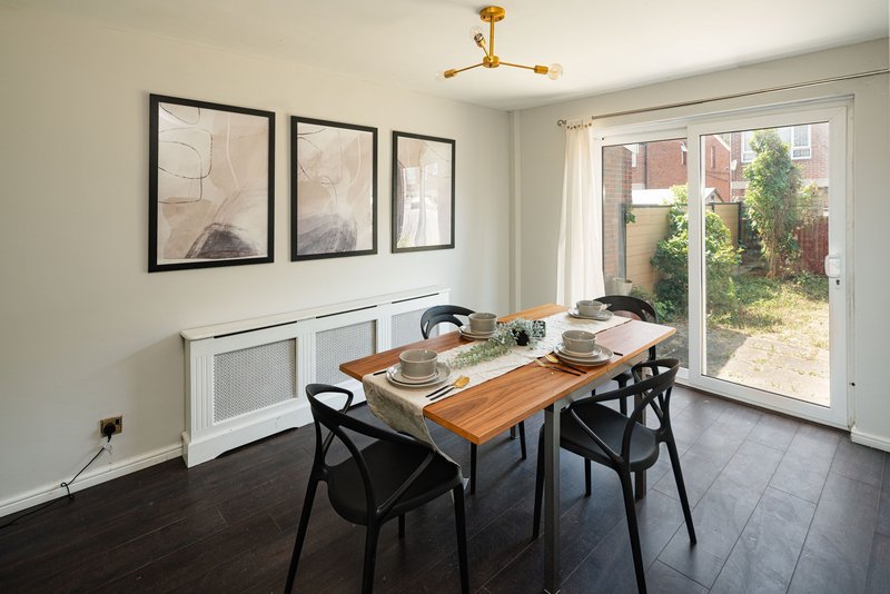 Dining room with wooden table, black chairs, framed wall art, and glass doors to garden