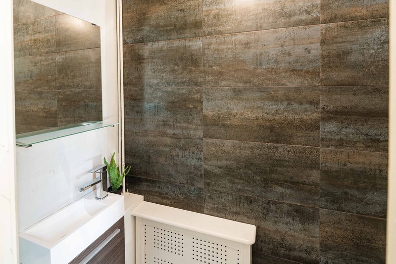 Modern bathroom with walk-in shower, white sink vanity and bronze tile walls