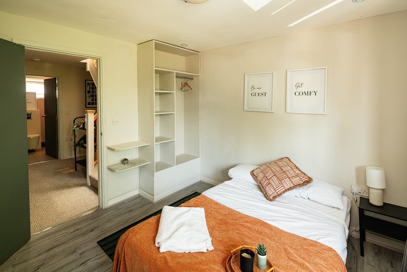 Bedroom with double bed, orange throw, built-in wardrobe and wall art