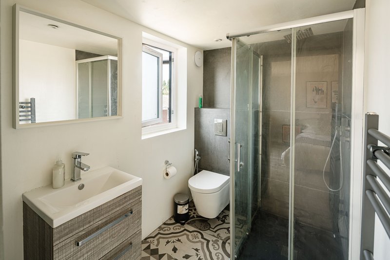 Modern bathroom with vanity sink, toilet, walk-in shower enclosure and heated towel rail