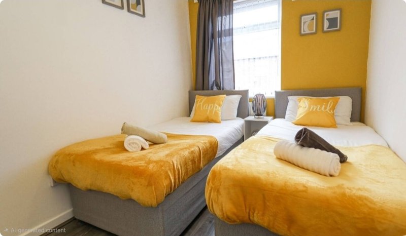Twin bedroom with two single beds, yellow bedding, pillows and rolled towels
