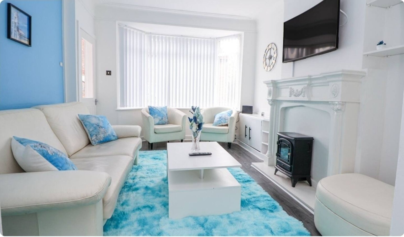 Bright living room with cream sofa, turquoise accents, fireplace and wall-mounted TV