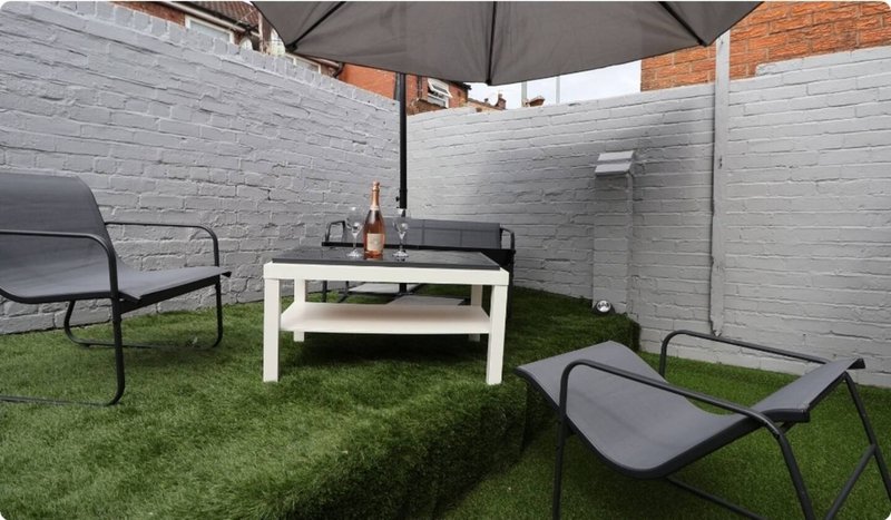 Outdoor patio area with white table, loungers, umbrella and painted brick walls