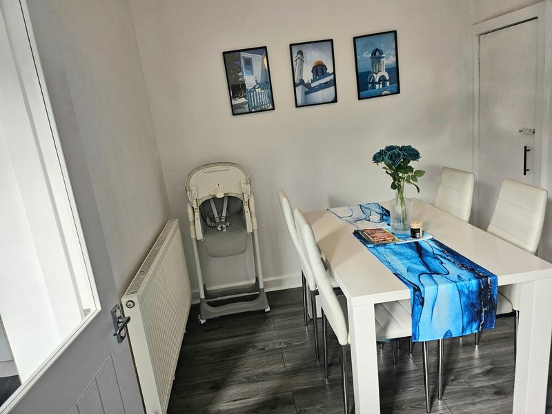 Dining area with white table, chairs, folding chair, framed wall art and flowers