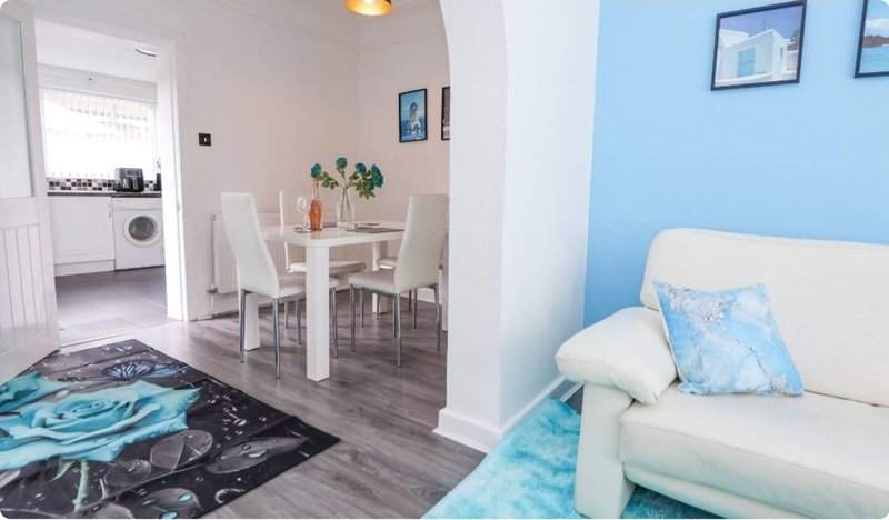 Open-plan living area with sofa, dining table, kitchen, and washing machine visible