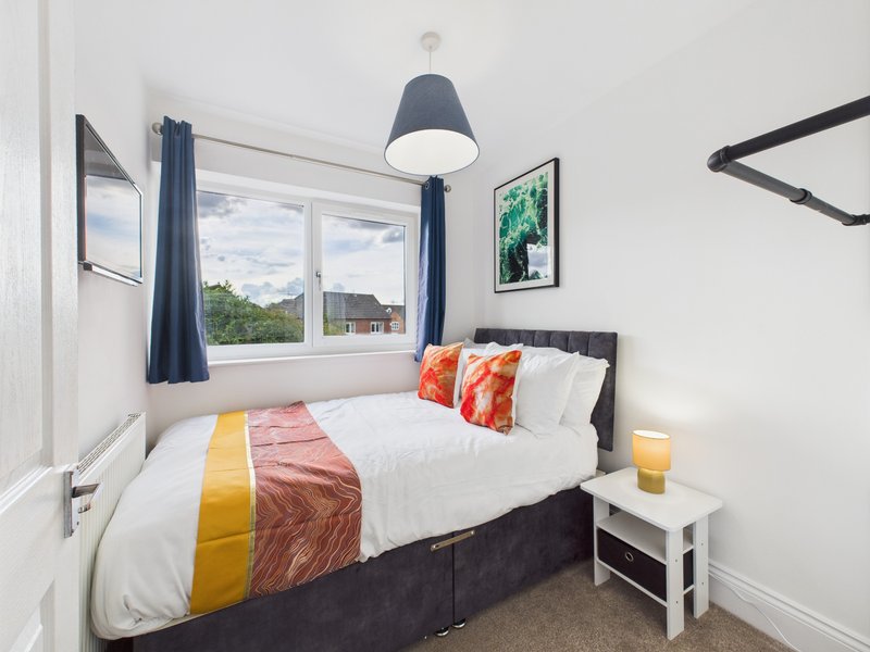 Bedroom with double bed, orange cushions, pendant lamp and window view