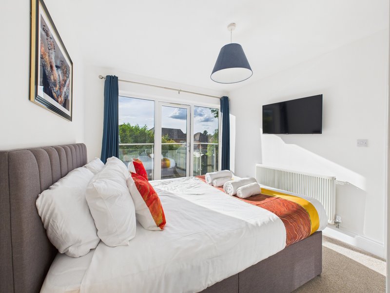Modern bedroom with double bed, wall-mounted TV, pendant lamp and garden view