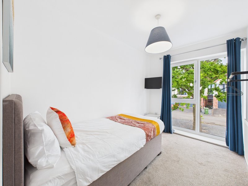 Bright bedroom with double bed, pendant light, and glass doors opening to garden