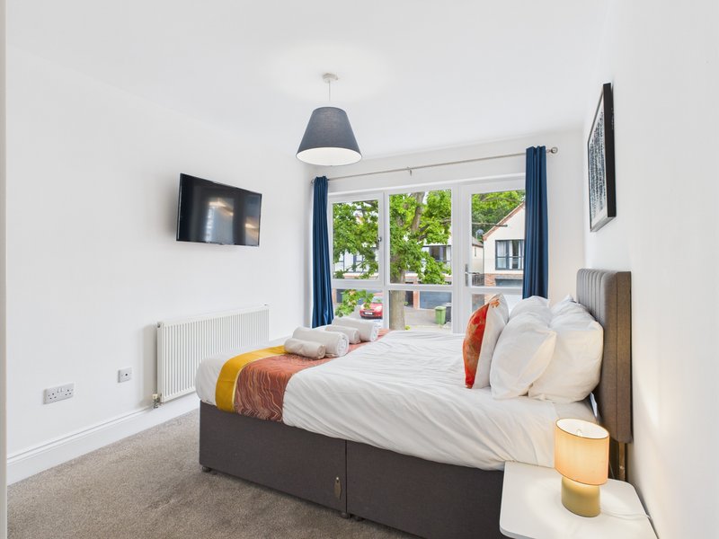 Bright bedroom with double bed, pendant lamp, wall art, and garden view through patio doors
