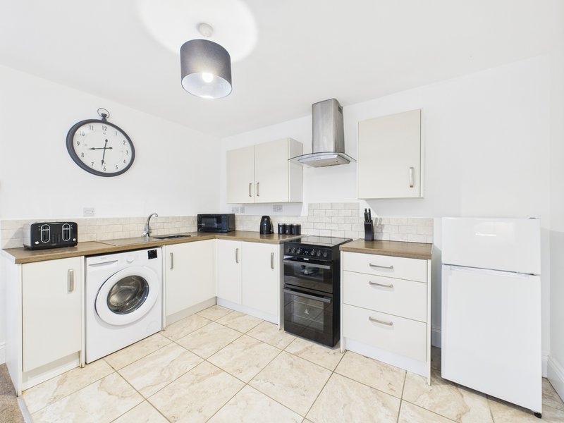 Modern kitchen with white cabinetry, wooden countertops, stainless steel appliances and tile flooring