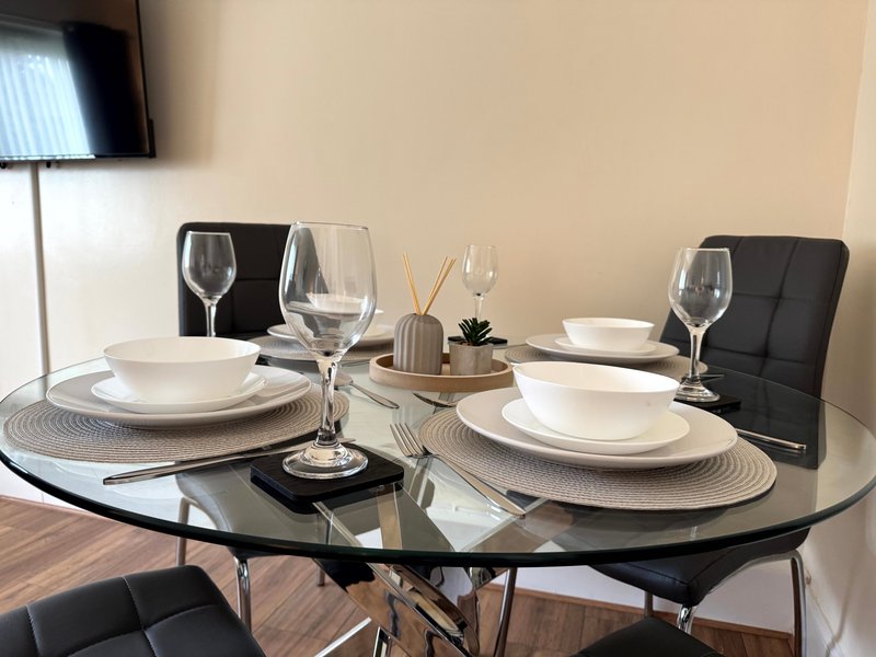 Modern dining table set with place settings, glasses, and decorative centerpiece