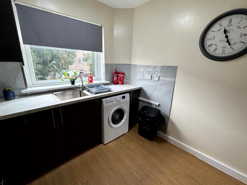 Utility room with black cabinetry, sink, washing machine, and wall clock