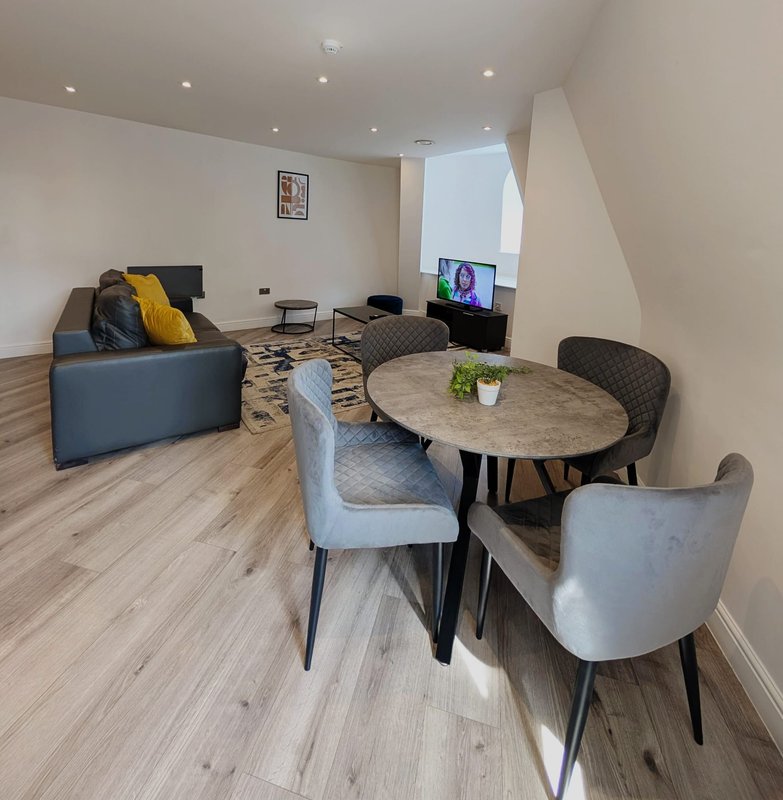 Open-plan living and dining area with sofa, round table, chairs and TV