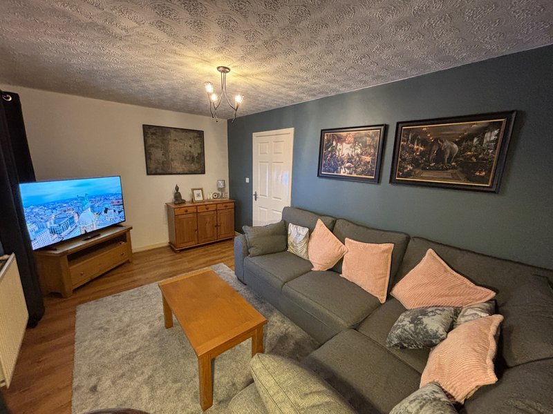 Living room with grey sofa, wooden coffee table, TV, framed artwork and cushions