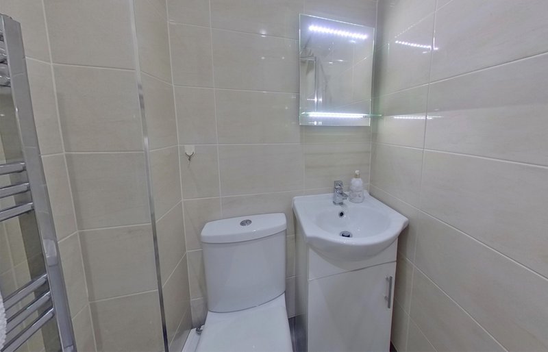 Small bathroom with toilet, sink, mirror cabinet and tiled walls