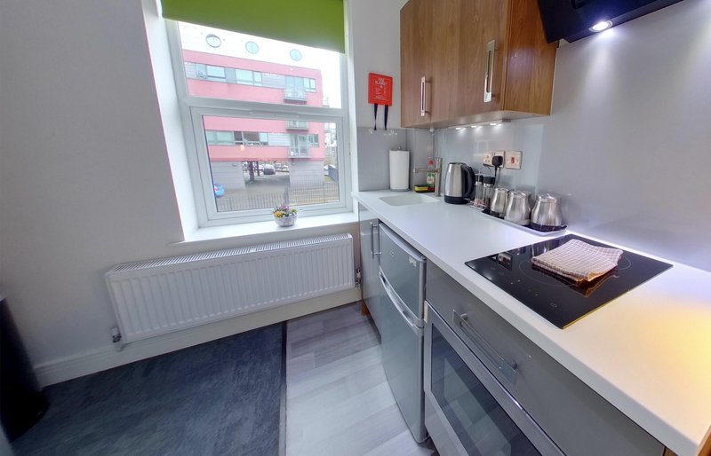 Modern kitchen with white countertops, wooden cabinets, induction hob and window view