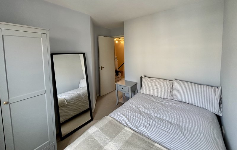 Small bedroom with two single beds, mirror, wardrobe and white walls