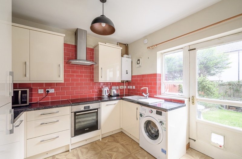 Modern kitchen with cream cabinets, red subway tile backsplash, and stainless steel appliances