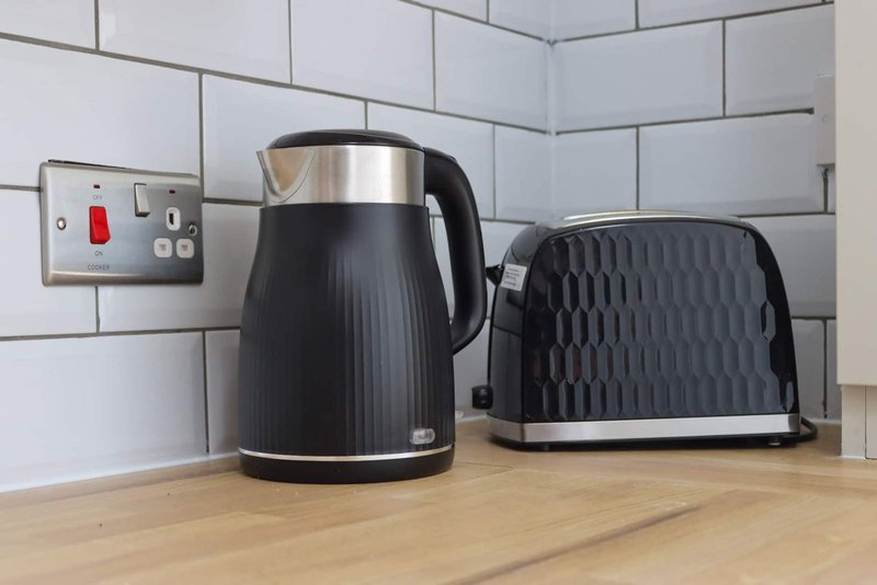 Kitchen counter with black kettle, toaster, and wall-mounted light switch