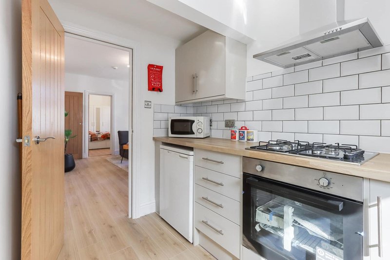 Modern kitchen with white subway tiles, gas hob, oven, wood counters and hallway view