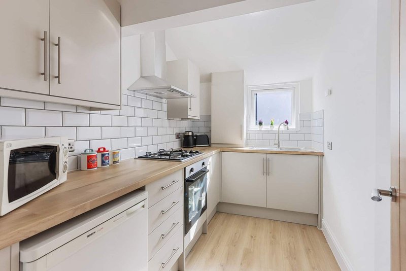 Modern kitchen with white cabinets, wooden countertop, stainless steel appliances and subway tile backsplash