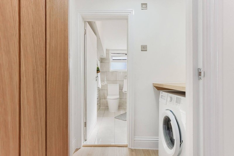 Hallway with wooden door, washing machine, and open bathroom doorway