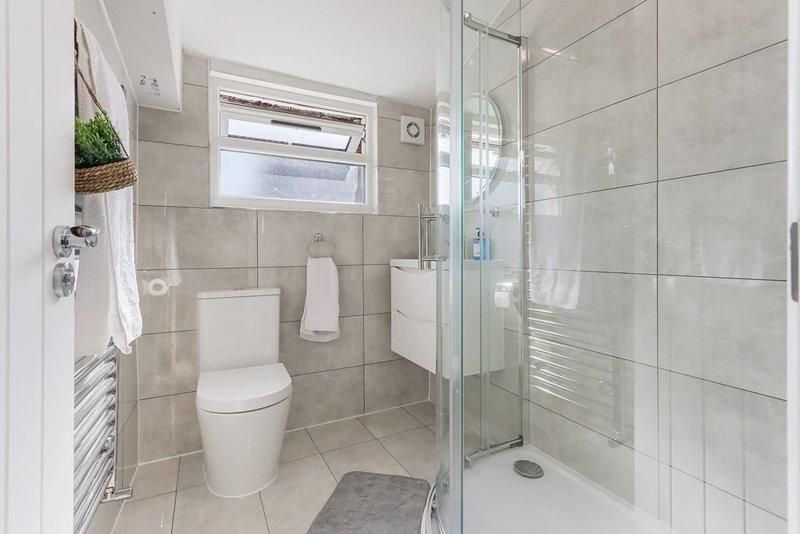 Modern bathroom with toilet, walk-in shower, heated towel rail and window