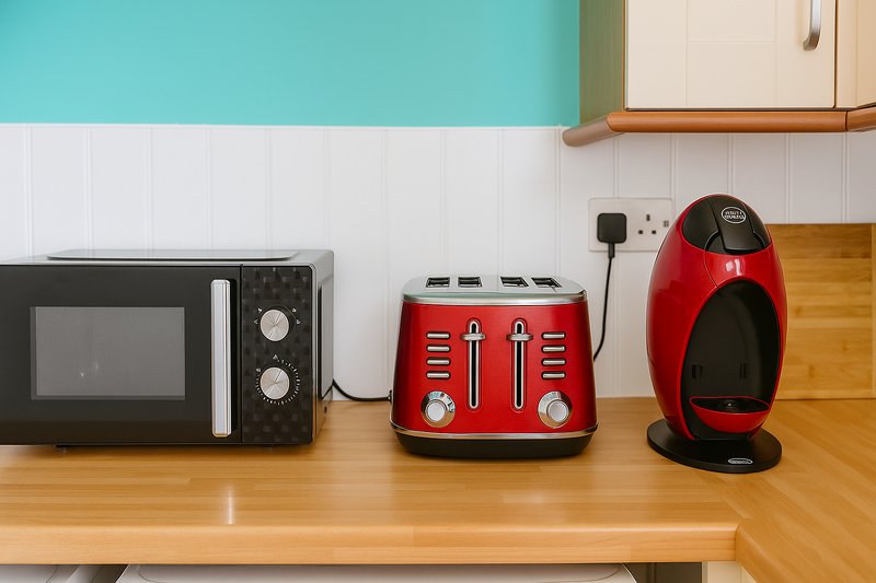 Kitchen counter with black microwave, red toaster, and red coffee machine on wooden surface
