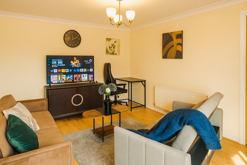 Bright living room with tan walls, sofa, TV, wooden flooring and contemporary furniture