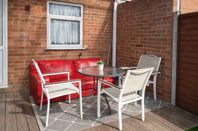 Brick patio with red sofa, white chairs, and small table in outdoor seating area