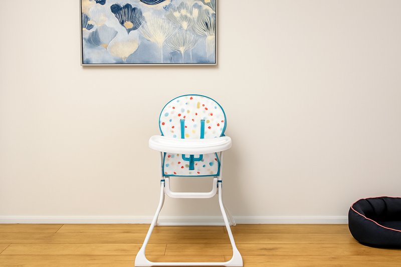 Modern nursery interior with white high chair, framed botanical artwork, wooden floor
