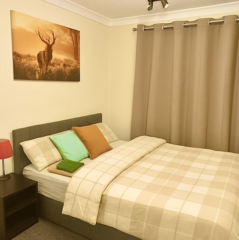 Bedroom with double bed, green headboard, patterned bedding, decorative pillows and wall art