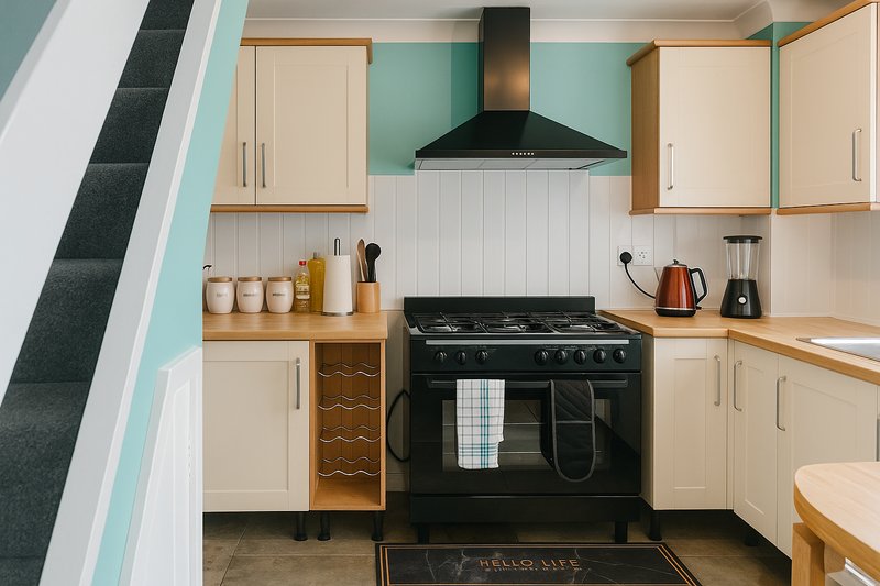 Modern kitchen with cream cabinets, black range cooker, turquoise walls and wooden worktops