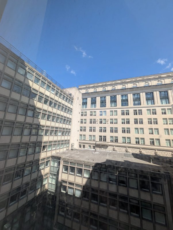 View of surrounding urban buildings with blue sky, taken from accommodation window