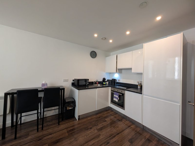 Modern kitchen with white cabinetry, black countertop, dining table and chairs