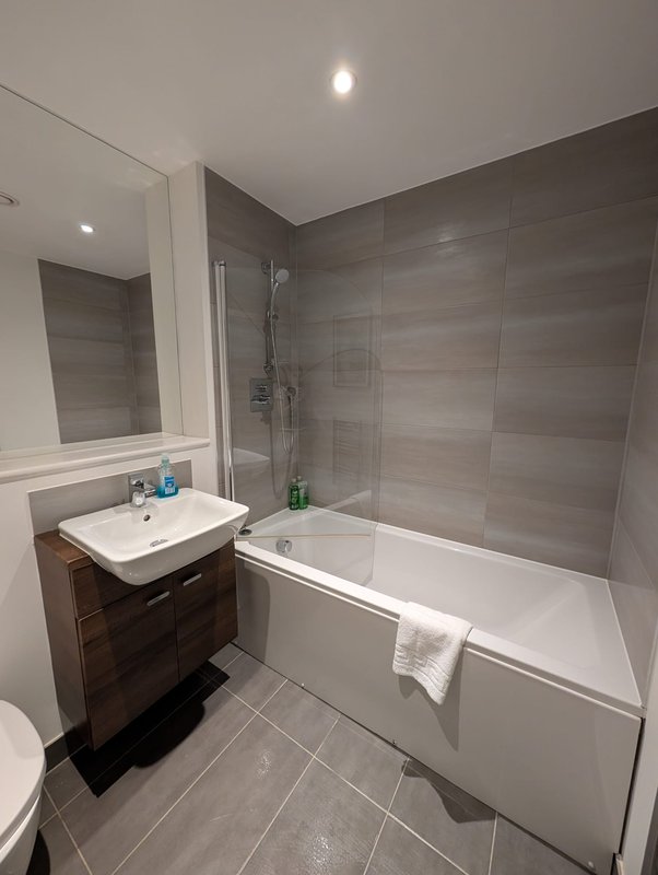 Modern bathroom with vanity sink, bathtub, shower enclosure and grey tile walls
