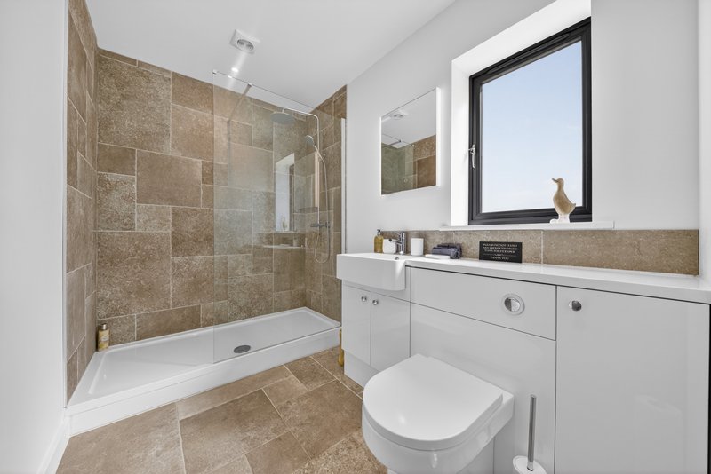Modern bathroom with walk-in shower, white vanity, toilet, and large mirror