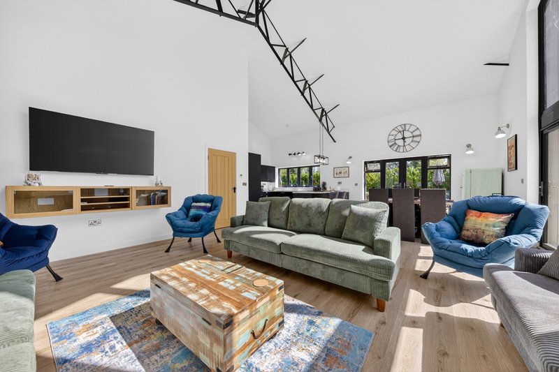 Modern living room with green sofa, blue armchairs, wooden coffee table and wall-mounted TV