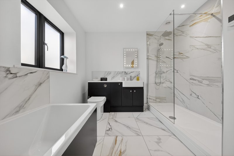 Modern bathroom with freestanding tub, black vanity, marble tiles and walk-in shower