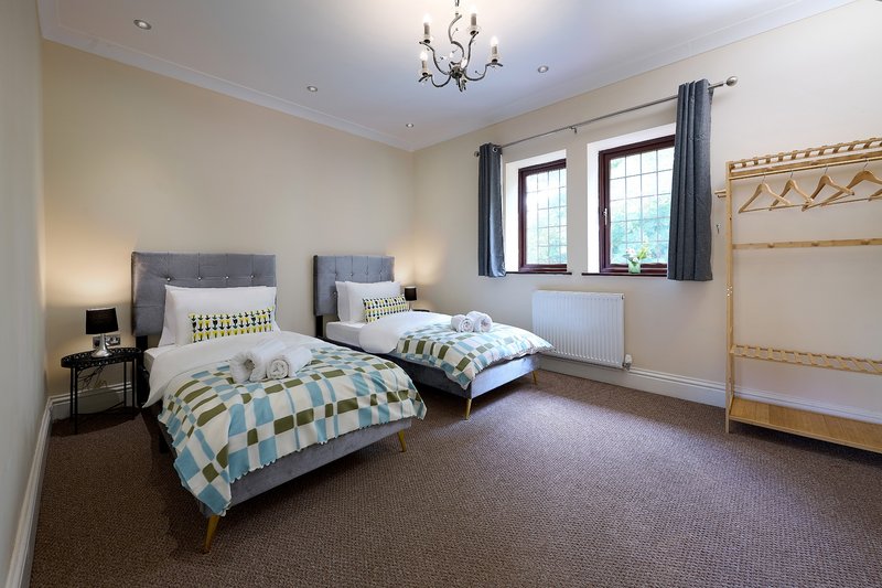 A bright, generous twin bedroom offering two comfortable single beds, with ample hanging space and a comfortable, clean environment to relax in after a busy day.