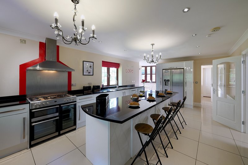 A large, kitchen designed with group stays in mind, featuring a generous central island with plenty of seating and workspace. The extensive cooking facilities make it ideal for larger groups