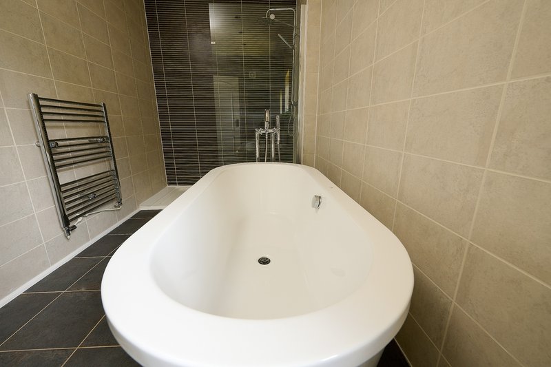 The property offers a generous number of bathrooms, providing plenty of convenience for larger groups. This bathroom features a freestanding bathtub, separate walk-in shower and heated towel rail.